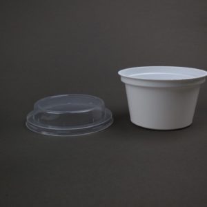 A white container and plastic lid on a table.